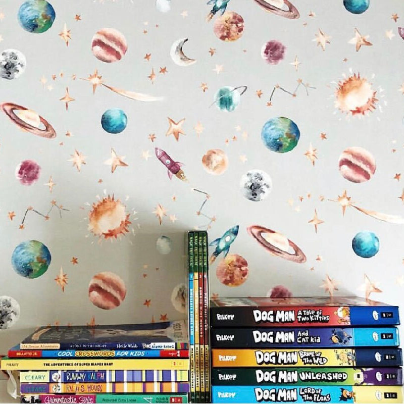 Wall with space-themed wall decals and a stack of books on a shelf.