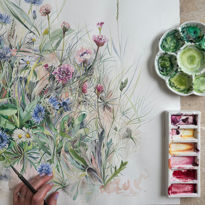 Hand painted watercolour illustration of wild flowers with a colour palette and paintbrush on a white surface