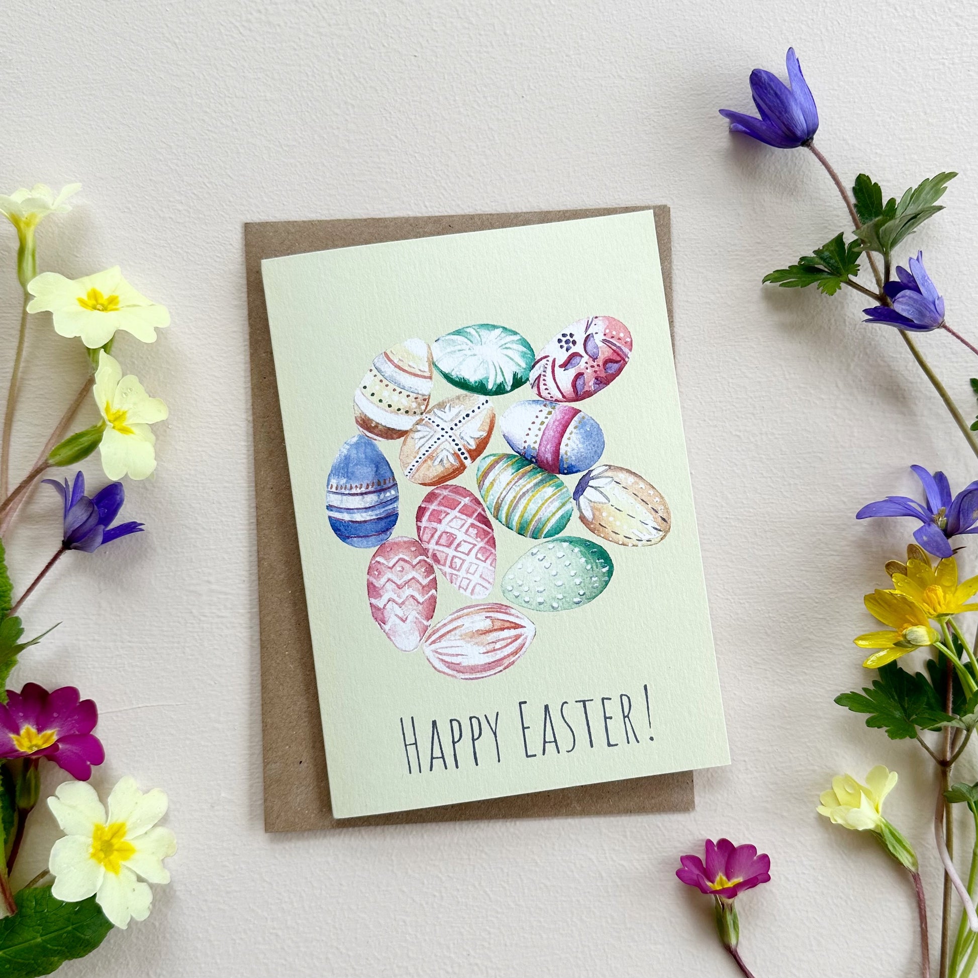 Easter card with colorful eggs and 'Happy Easter!' text, surrounded by spring flowers on a light background