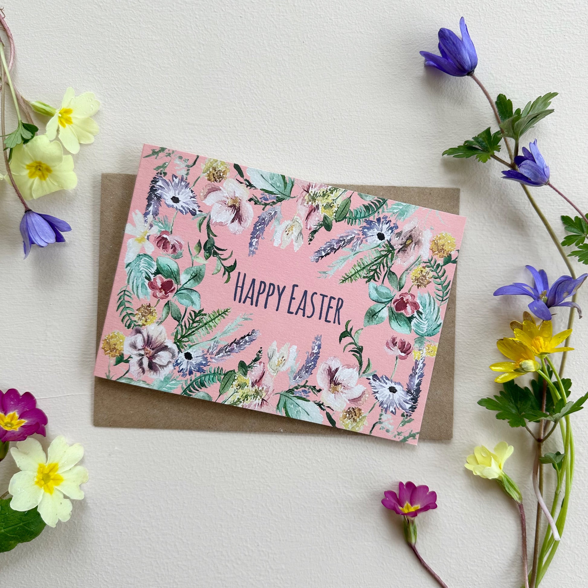 Floral Easter card with 'Happy Easter' text on a pink background, card surrounded by flowers.
